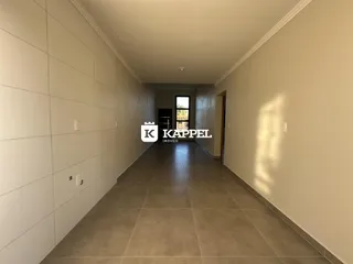 Corredor interno com piso de cerâmica e paredes claras.