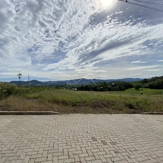 Vista externa de uma paisagem com colinas verdes sob um céu nublado.