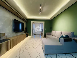 Sala de estar com sofá e televisão em ambiente com paredes verde-água.