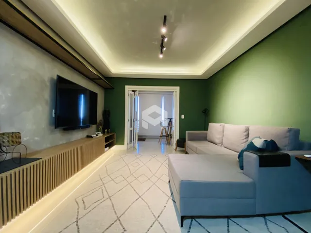 Sala de estar com sofá e televisão em ambiente com paredes verde-água.