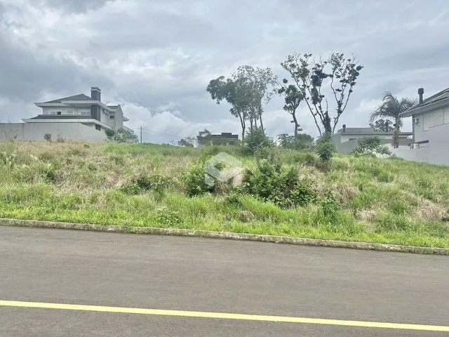 Vista externa de casas em Lajeado, Brasil, com vegetação densa no primeiro plano.