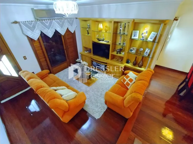 Sala de estar com sofá laranja e piso de madeira.
