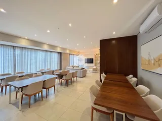 Uma sala de jantar ampla com mesas e cadeiras em um imóvel.