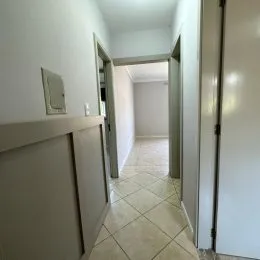 Corredor interno com piso de cerâmica e paredes brancas.