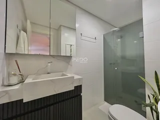 Interior de um banheiro moderno com revestimento branco e bancada de mármore.