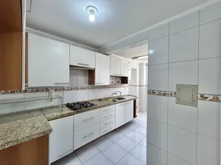 Uma cozinha com armários brancos e bancadas de granito.