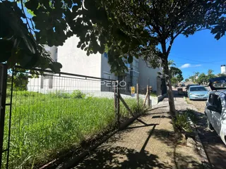 Fachada de uma residência branca com cerca e vegetação no primeiro plano.