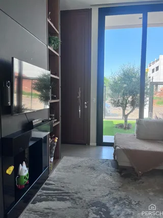 A sala de estar apresenta um sofá e uma porta de vidro que dá acesso ao exterior.