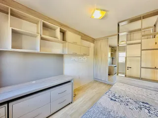 Quarto com armários planejados e piso de madeira clara.
