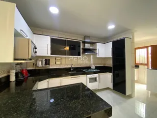 Cozinha moderna com armários brancos e bancadas escuras.