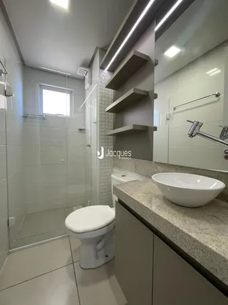 Banheiro moderno com box de vidro e revestimento cerâmico.