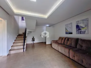 Sala de estar com sofá e escadaria em um ambiente claro.