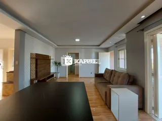 Sala de estar com piso de madeira e sofá de cor neutra.