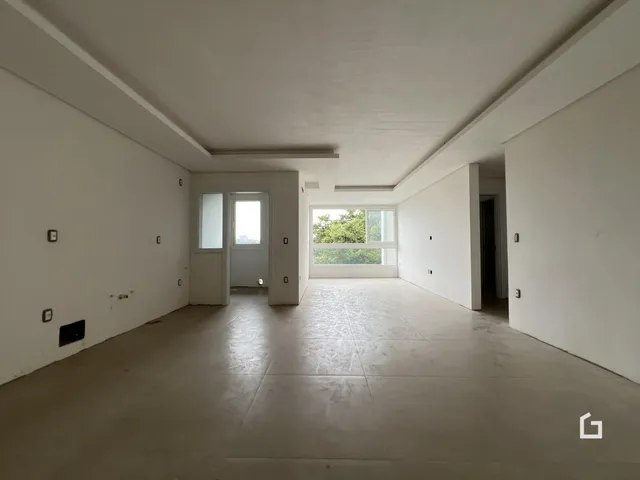 Interior de uma sala ampla com paredes brancas e piso claro.