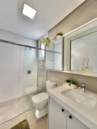 Foto de um banheiro moderno com box de vidro e louças brancas.