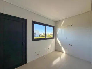 Vista interna de um cômodo com paredes brancas e uma janela.