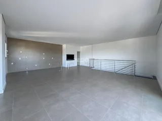 Ambiente interno de uma sala ampla com piso de cerâmica e paredes brancas.