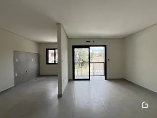 Interior de uma sala com paredes brancas e piso de concreto.