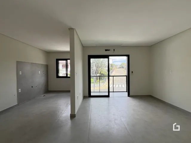 Interior de uma sala com paredes brancas e piso de concreto.