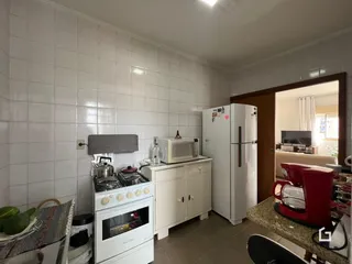 Imagem de uma cozinha com revestimento de cerâmica branca e eletrodomésticos.