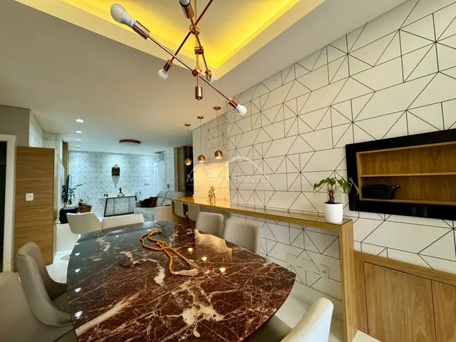 Sala de jantar com mesa de mármore escura e decoração moderna.