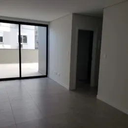 Vista interna de uma sala com piso de cerâmica e porta de vidro.