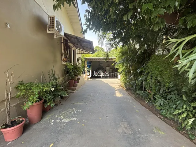 Vista da fachada de uma residência com jardim e vegetação ao redor.