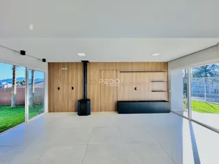 Sala de estar ampla com revestimento de madeira e portas de vidro que dão acesso ao jardim.