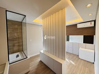 Vista de um banheiro moderno com box de vidro e piso de madeira clara.