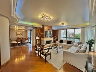 Sala de estar ampla com piso de madeira e lareira em um imóvel no Brasil.