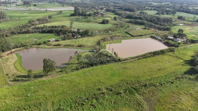 Vista aérea de uma área rural com campos verdes e corpos d'água.