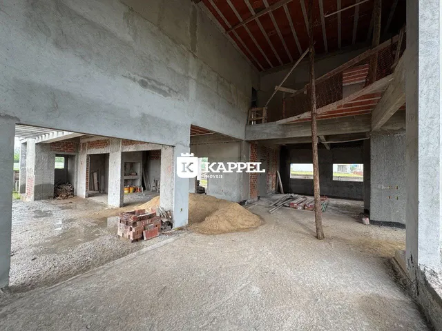 Foto de uma estrutura em construção com paredes de concreto aparente e vigas expostas.
