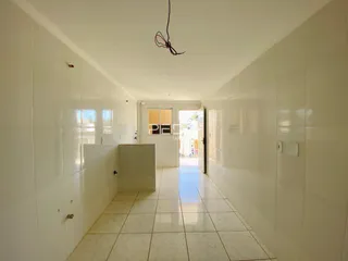 Corredor interno de um imóvel com piso de cerâmica claro.