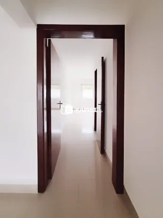 Corredor interno com portas de madeira escuras e paredes brancas.