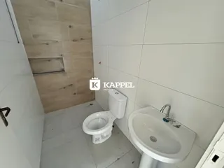 Foto de um banheiro com louças brancas e revestimento de parede claro.