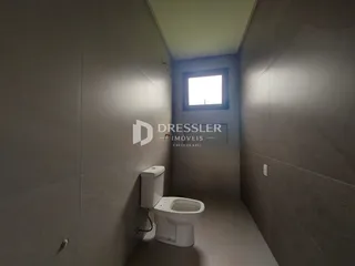 Um corredor estreito com um vaso sanitário e uma janela no final.