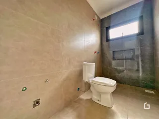 Uma foto de um banheiro com revestimento de cerâmica clara e detalhes em mármore escuro.