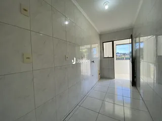 Corredor interno com piso e paredes brancas de cerâmica.