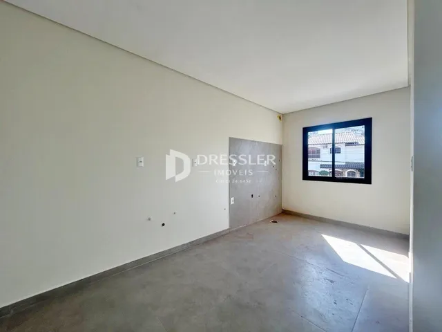 Vista interna de um ambiente com paredes brancas e piso de concreto.