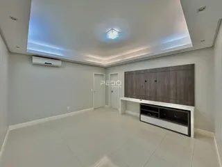 A sala de estar apresenta um design moderno com piso claro e iluminação embutida.