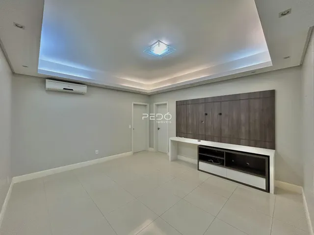 A sala de estar apresenta um design moderno com piso claro e iluminação embutida.