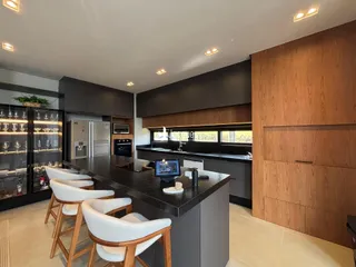 Vista da cozinha moderna com ilha e armários escuros.
