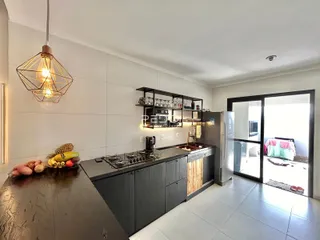 Vista da cozinha moderna com armários escuros e bancadas claras.