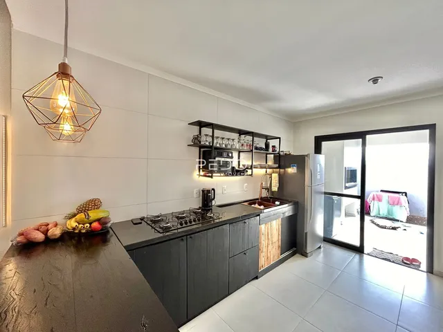Vista da cozinha moderna com armários escuros e bancadas claras.