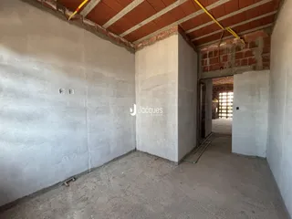Interior de uma área com paredes de concreto e teto de tijolos exposto.