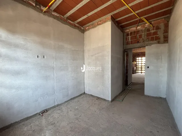 Interior de uma área com paredes de concreto e teto de tijolos exposto.
