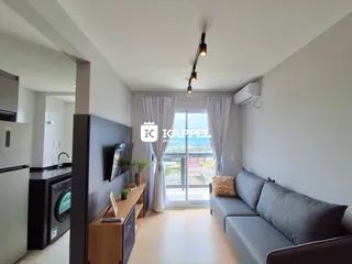 Sala de estar com sofá e porta de vidro que oferece vista para o exterior.