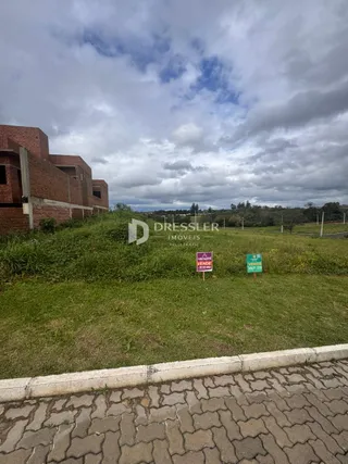 Vista externa de uma propriedade com gramado e um edifício de tijolos.