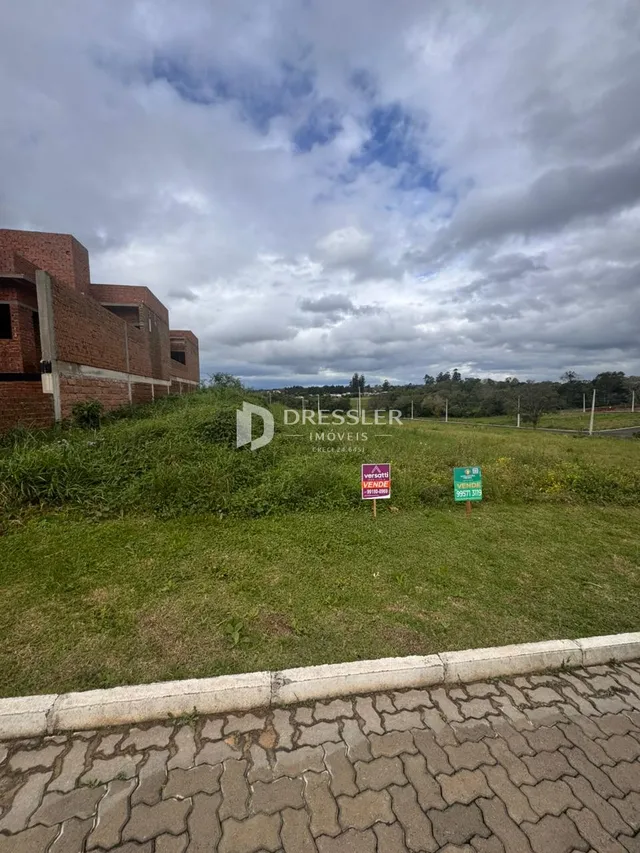 Vista externa de uma propriedade com gramado e um edifício de tijolos.