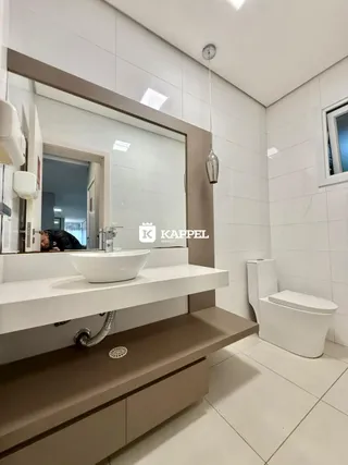 Banheiro moderno com bancada branca e revestimento de azulejos brancos.